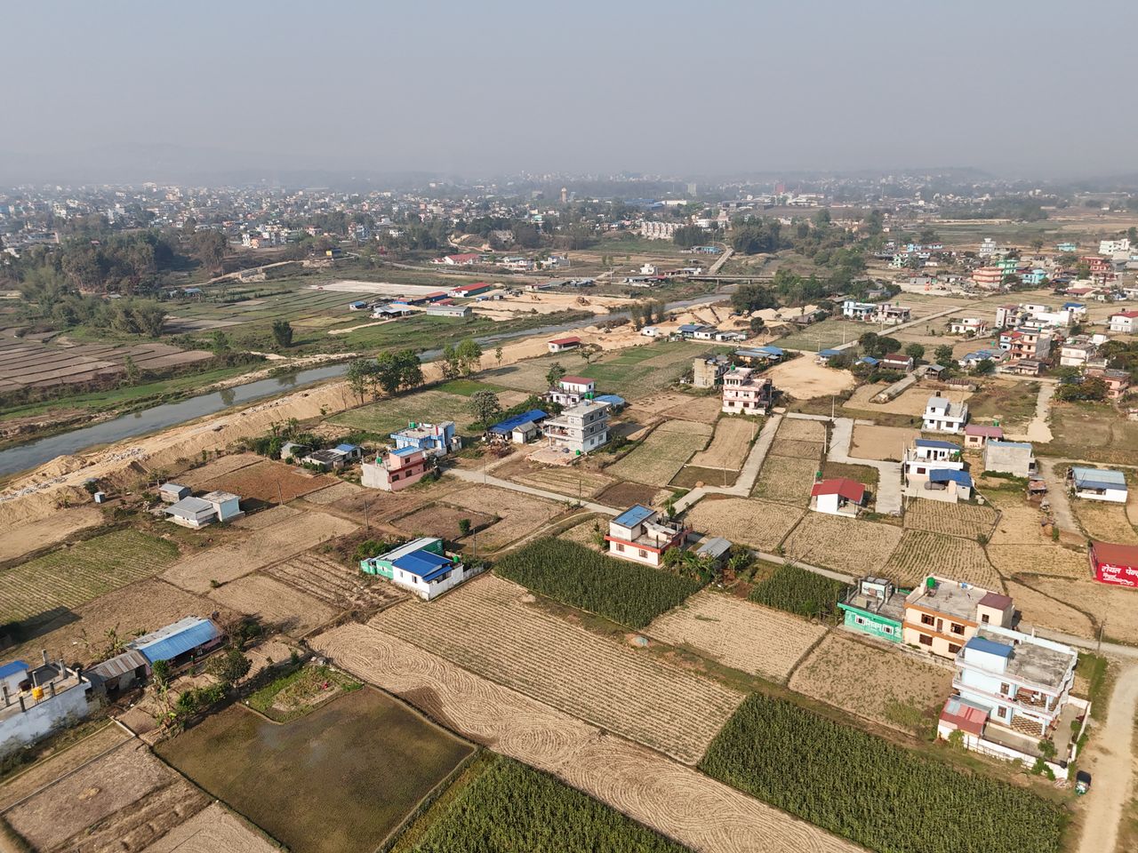 Aerial shot of a rural village in Nepal showcasing fields and scattered houses.